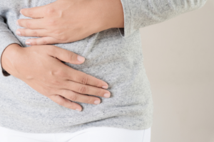 Picture of person with bloating and hands held over their stomach