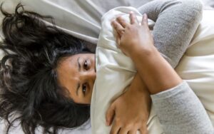 Woman clutching pillow with panic attack due to Pyschosomatic Disorder