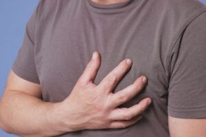 Suzy Cohen 67 Man clutching chest experiencing mild arrhythma