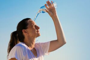 Woman pouring water on herself due to summer fatigue
